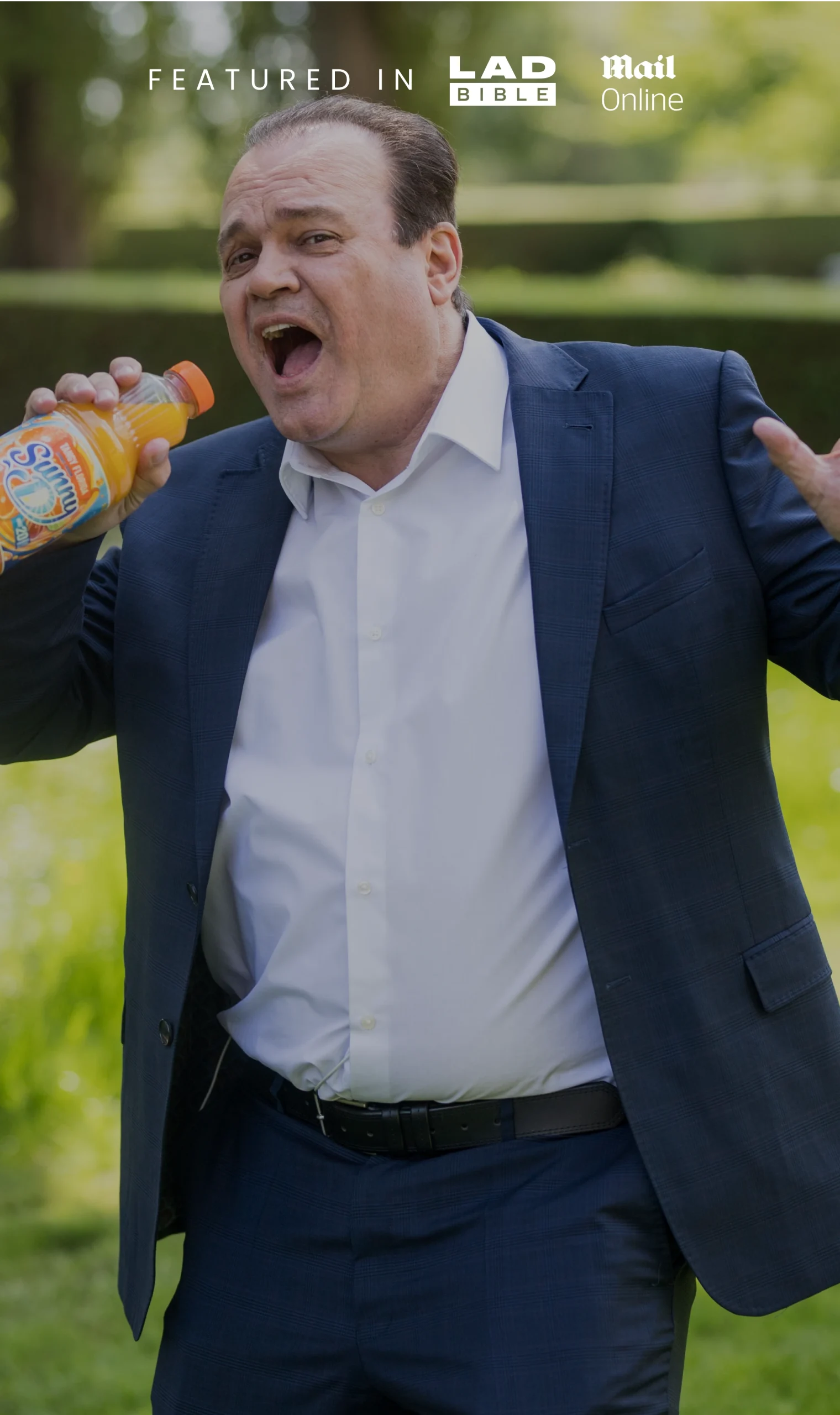 A person in a suit holding a bottle of juice